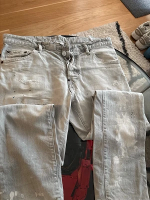 Dsquared2 jeans ( äkta vintage )  - Säljer ett par grå jeans från Dsquared2 med coolt distressed utseende, slitningar och färgstänk. Jeansen har klassisk femficksmodell och smal passform. Tillverkade i bomull med en snygg tvättad finish och detaljer som ger en unik look.