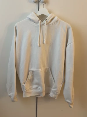 Vit hoodie med magficka och huva - Klassisk vit hoodie med stor magficka och justerbar huva med dragsko. Från BikBok i storlek XS. Perfekt för en avslappnad och stilren look. Materialet känns mjukt och bekvämt. Gåva vid köp!🎁