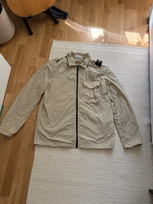 Stone Island overshirt - Säljer denna tunna sköna och framför allt snygga overshirten från stone island. Jackan har luft hål i armhålorna och är tunn så helt optimal för varmare sommardagar. Jackan är självklart äkta och har endast blivit använd ett par gånger. Nypris: 3899kr Storlek: XL Mått: Axel-Axel 49cm Armhåla-Armhåla 61cm Längd 72cm