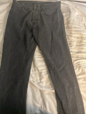 Svarta raka jeans Carhartt - Säljer ett par svarta raka jeans från Carhartt med klassisk femficksdesign och normal midja. Jeansen har en enkel look utan synliga loggor och är tillverkade i ett slitstarkt denimtyg. Perfekta för dig som gillar en clean och tidlös stil.