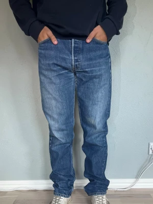 Levi's 501 W32 L34 – Vintage fade, straight fit | 100% bomull - LEVI’S 501 ORIGINAL  Storlek: W32 L34 Passform: Straight fit, hög midja Material: 100% bomull Jeansen sitter oversized/baggy på modellen som normalt bär W30 — passar dig som vill ha ett lösare och mer avslappnat sitt.  Klassiska 501:or med fin naturlig fading och whiskering vid grenen — den typ av tvätt som bara kommer med åren. Knappgylf som det ska vara på en äkta 501.  Modellen på bilden är 175cm och väger 65kg.  Skick: Bra vintage-skick. Normalt slitage för åldern. Nypris: ca 1 299 SEK. 