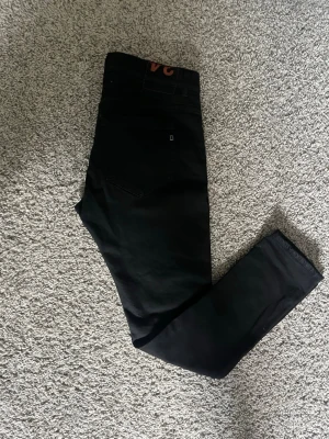 Svarta jeans från Dondup storlek w38 54 - Säljer ett par snygga svarta jeans från Dondup, tillverkade i Italien. Jeansen har klassisk femficksdesign och en slim fit passform. Materialet är mjukt och stretchigt vilket gör dem bekväma att bära. Perfekta för dig som vill ha ett stilrent och modernt plagg.