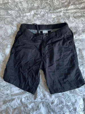 Svart shorts med snörning från Jack & Jones - Snygga svarta shorts från Jack & Jones med snörning i midjan och avslappnad passform. Tillverkade i mjuk bomull, perfekta för varma dagar. Två fickor fram och två bakfickor för en klassisk look.
