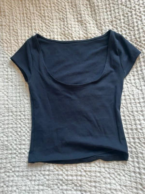 Svart croppad topp med djup urringning bak - En enkel och stilren svart croppad topp med korta ärmar och djup urringning bak. Tillverkad i mjukt bomullsmaterial som sitter skönt mot kroppen. Perfekt att matcha med jeans eller kjol för en clean look. OBS barn storlek 158/164