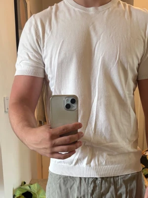 Vit basic t-shirt i bomull stickat - En klassisk vit t-shirt med rund hals och korta ärmar. Denna är i stickat material från Zara, sitter åt bra runt bröst och axlar och perfekt gör lite varmare sommarkvällar 