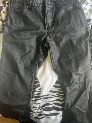 Svarta raka jeans - Säljer ett par svarta jeans med rak passform och klassisk femficksdesign. Jeansen har bälteshällor och stängs med dragkedja och knapp. Materialet är denim i bomull. Perfekta till en avslappnad stil.
