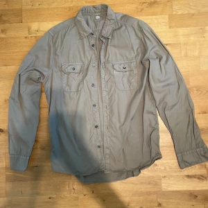 Beige skjorta från C.P. Company - Snygg beige skjorta från C.P. Company med klassisk krage, två bröstfickor med knappar och diskret logga ovanför fickan. Skjortan har långa ärmar och är tillverkad i mjuk bomull. (Är XL men sitter som L) Äkta såklart.