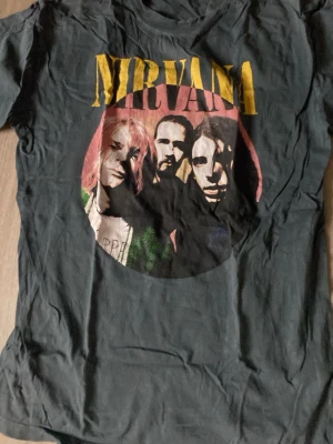 Svart Nirvana t-shirt med tryck - Cool svart t-shirt från Nirvana med stort färgglatt bandtryck på framsidan och klassisk rund hals. T-shirten har korta ärmar och är i loose fit, perfekt för en avslappnad stil. Tillverkad i mjuk bomull för skön känsla hela dagen.