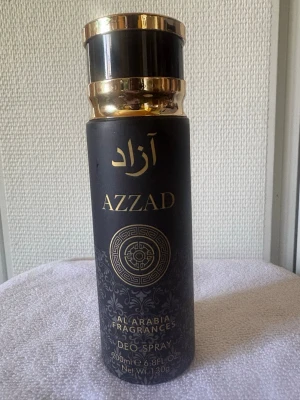Azzad deo spray från Al Arabia - Azzad deo spray från Al Arabia Fragrances med elegant svart och guld design. Flaskan är cylindrisk med dekorativa mönster och arabiska inslag. Rymmer 200 ml och har en lyxig känsla med metalliska detaljer. Perfekt för dig som vill ha en unik och stilren parfym.