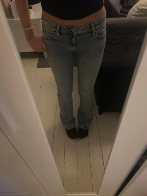 ljusblå bootcut jeans - Säljer ett par ljusblå raka jeans från Gina med snyggt slitna detaljer och broderade bakfickor. Jeansen har klassisk femficksmodell, låg midja och bälteshällor. 