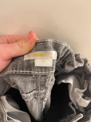 Gråa bootcut jeans från Gina Tricot - Säljer ett par gråa bootcut jeans från Gina Tricot. Jeansen har snygga bakfickor med lock och knappdetalj, samt klassisk femficksdesign. Materialet är mjukt denim med lätt tvättad look. Perfekta för en trendig och avslappnad stil.