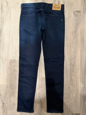 Nyskick - Replay Anbass Mörkblå W32/L34 - Slim Fit - Nytt mycket fint skick. Mått - Midja: 43cm, Ytterbenslängd: 106cm, Benöppning: 16cm. Modellen är 185cm & 63kg. Hör av dig vid funderingar!🤝