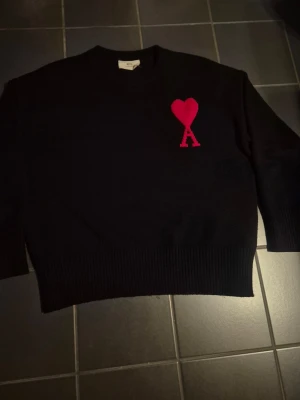 Ami Paris  - Säljer en authentiskt stickad tröja från Ami Paris | I färgen svart med röd logga och storlek S | Inga defekter | Hör av er om ni vill ha fler bilder!