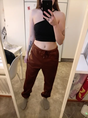 Bruna mjukisbyxor med dragsko - Säljer ett par bruna mjukisbyxor med dragsko i midjan och avslappnad passform. Byxorna har elastiska muddar vid benslut och är perfekta för chill dagar. Materialet känns mjukt och bekvämt mot huden.