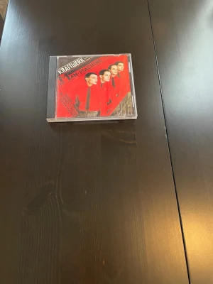 CD-album Kraftwerk och Sturm Café - Två CD-album: Kraftwerks 'Die Mensch-Maschine' i plastfodral med röd och svart omslagsdesign, samt Sturm Cafés 'Zeitgeist' i pappersfodral med mörkt omslag och blixtsymboler. Perfekt för dig som gillar elektronisk musik och samlar fysiska album.