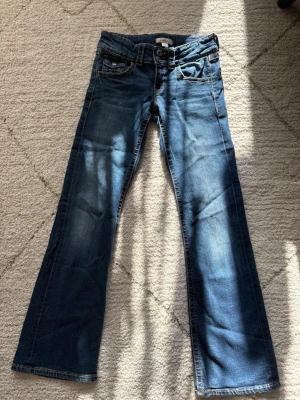 Mörkblå bootcut jeans - Snygga mörkblå bootcut jeans med klassisk femficksdesign och lätt slitningar framtill. Jeansen har normal midja och raka ben som går ut lite nedtill för en avslappnad look. Perfekta till sneakers eller boots.
