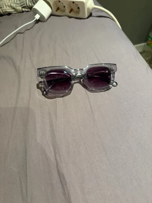 Grå CHIMI solglasögon - Säljer ett par stilrena solglasögon från CHIMI med grå transparent båge och mörka glas. Klassisk rektangulär form som passar till många olika looks. Bågarna är tillverkade i syntetmaterial och har diskret CHIMI-logo på sidan. Skriv om ni har frågor eller funderingar. Fraktar bara genom PostNord 
