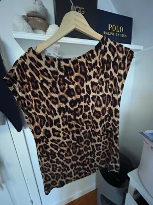 Leopardmönstrad topp från lager 157 - Snygg topp med leopardmönster i beige och bruna toner. Modellen är ärmlös med rund halsringning och har en loose passform. Perfekt för dig som vill sticka ut lite extra. Materialet känns mjukt och följsamt, troligen polyester eller bomull.