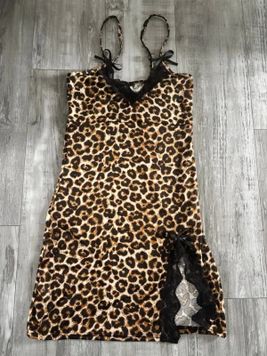 Leopardmönstrat nattlinne med spets Shein - Snyggt leopardmönstrat nattlinne med tunna axelband och svarta spetsdetaljer vid urringning och slits. Dekorativa rosetter framtill och vid slitsen. 