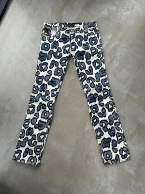 Leopardmönstrade jeans från Lee - Säljer ett par unika jeans från Lee med blått och svart leopardmönster på vit botten. Modellen har klassisk femficksdesign och lite utsvängda nedtill. (W 83cm, innebenslängd 80cm). Skriv för frågor💕