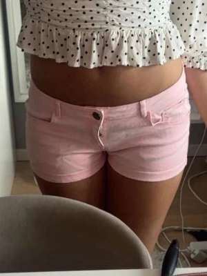 Rosa jeansshorts - Snygga ljusrosa shorts med klassisk femficksdesign och knappstängning fram. Modellen är kort och har bälteshällor, perfekt för varma dagar. Passformen är normal och materialet känns som bomull. Aldrig använda