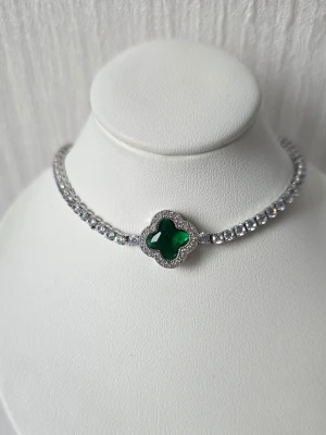 armband med grön fyrklöver - Snyggt armband i silverfärg med gnistrande stenar och en grön fyrklöverformad detalj i mitten. Armbandet har en klassisk tennisdesign de tätt sittande stenarna och ett smidigt spänne. Perfekt för dig som gillar stilrena accessoarer med en sop touch. Justerbar i storlek, finns även i andra färger