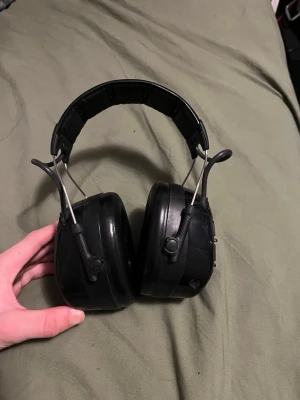 3M Peltor WorkTunes Pro hörselkåpor - Säljer ett par svarta 3M Peltor WorkTunes Pro hörselkåpor med inbyggd radio och  stora öronkåpor. Skickar med en bluetooth adapter så det går o lyssna på musik!                   De har vadderad huvudbygel, robust design i plast och metall samt knappar för volym och ström på sidan. Perfekta för att lyssna på musik samtidigt som du skyddar hörseln. 