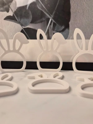 Vita servettringar med kaninöron 6st - Säljer 6st söta vita servettringar formade som kaninhuvuden med långa öron. Perfekta för att ge din dukning en fin och personlig touch. Tillverkade i plast och har en stilren, minimalistisk design.