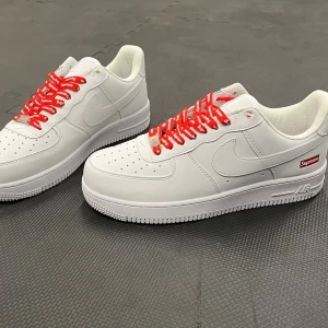 Nike x Supreme vita sneakers - Fräscha vita Nike Air Force 1 sneakers i samarbete med Supreme. Skorna har röda skosnören med Supreme-logga och en liten Supreme-tag på sidan. Tillverkade i slätt läder med klassisk Nike-sula och perforerad tå för extra ventilation. Utan box 