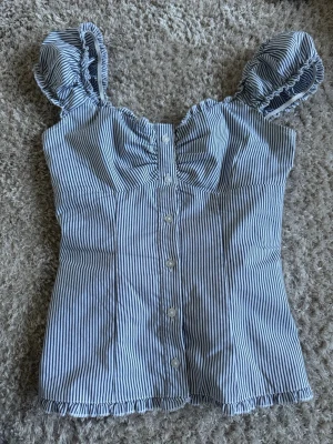 Randig blus från Hollister - Supersöt blus från Hollister med blå och vita ränder. Finns nästan inga tecken på användning❤️ köpte i USA 🌟