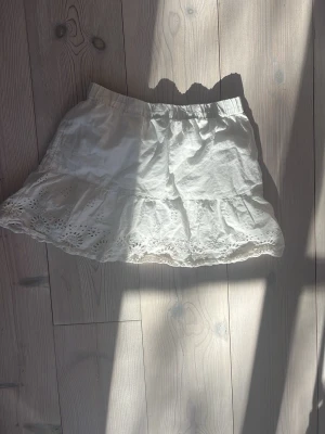 Vit volangkjol - Söt vit kortkjol från Kappahl med volang och broderade spetsdetaljer längst. storlek 158 cm men passar typ xs-m skulle jag säga❣️