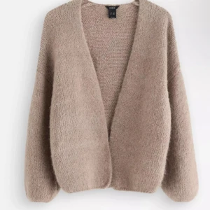 Beige stickad kofta från Lindex - Mysig beige stickad kofta från Lindex med oversized passform och lite kort i ärmar. Koftan har en öppen front utan knappar och är perfekt att slänga på sig när det är kyligt. Koftan är i storlek xs/s och är bara använd 3 gånger. 