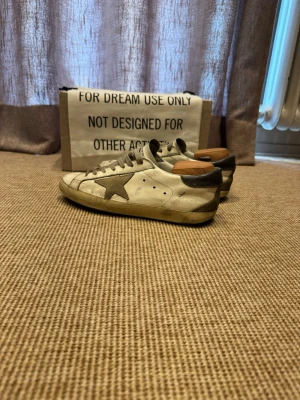 Golden Goose vita sneakers med stjärna - Säljer mina Golden Goose för att de är för små. Ny pris 5000kr. Snygga skor som passar till sommaren. Sulan är fast limmad och sitter fast jätte hårt