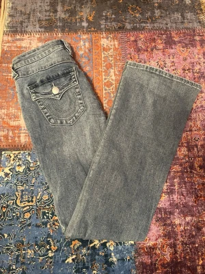 True religion jeans  - Säljer ett par jättefina ljusblåa true religion jeans från Nelly. Jeansen är helt oanvända och endast testade! Modellen heter Becca i storleken 28 som motsvarar en M och har en medelhög midja. Nypriset är 1299kr🤍
