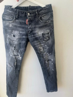 Dsquared 2 Jeans  - Coola grå jeans från Dsquared2 med distressed detaljer, slitningar och paint splatter-effekt. Klassisk femficksmodell med en extra liten ficka fram. Jeansens material är denim och de har en modern, smal passform. Perfekt för dig som gillar en edgy streetstyle. Passar någon som är mellan 170-174cm. Ny pris 7500