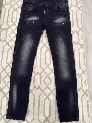Svarta slim fit jeans med slitningar - Snygga svarta slim fit jeans med slitningar och blekta partier på både fram- och baksida. Jeansen har klassisk femficksdesign och smal passform. Perfekta för en trendig och avslappnad look.