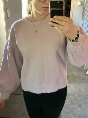 Ljuslila sweatshirt med ballongärm - Trendig ljuslila sweatshirt med ballongärmar och ribbade muddar vid ärmslut och nederkant. Oversized passform som ger en avslappnad look. Perfekt att matcha med jeans eller kjol för en cool vardagsstil.