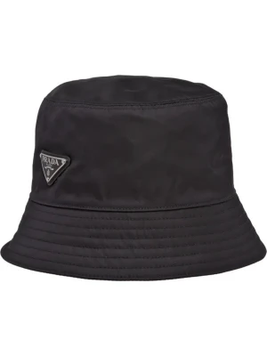 Svart bucket hat från Prada - Stilren svart bucket hat från Prada med klassisk form och diskret logga på sidan. Hatten är tillverkad i ett syntetmaterial som ger en lätt och modern känsla. Perfekt accessoar för att lyfta din outfit. Box följer med!