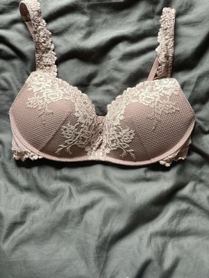 Rosa spets-bh med vaddering från intimissimi  - Söt bh i ljusrosa med vadderade kupor och vacker spetsdetalj framtill och på axelbanden. Bh:n har justerbara axelband och hakknäppning bak. Materialet är en mix av spets och mjuk microfiber för extra komfort. Aldrig använd 