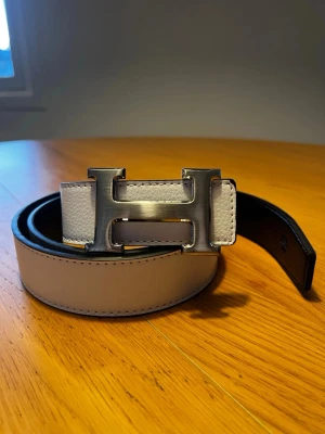 H-ermes Bälte - Snyggt skärp  i vitt med ikoniskt H-spänne i silverfärgad metall. Perfekt accessoar för att lyfta din outfit med en lyxig touch och klassisk design. Snyggt svart skärp med ikoniskt H-format metallspänne i silverfärg. 120cm. Helt nytt skärp. Meddela vid intresse, skickar samma dag som det köps! 