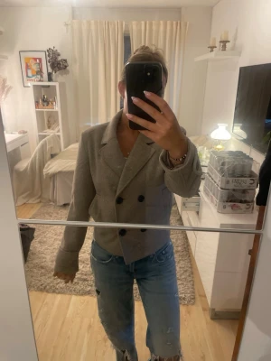 Beige dubbelknäppt kappa från Only - Kort beige kappa från Only med dubbelknäppning och bred krage. Kappan har två framfickor och stora svarta knappar. Tillverkad i ett mjukt ull-liknande material och helfodrad för extra komfort. Den är i storlek M men sitter bra på mig som vanligtvis är en xs/s Perfekt för en trendig och stilren look. knappt använd!