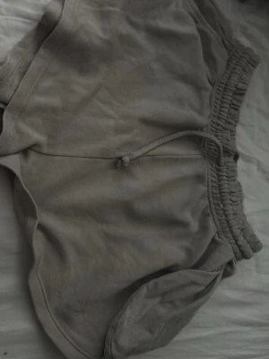 Gråa mjuka shorts  - Ett par gråa shorts i mjukt material med elastisk midja och snörning framtill. 