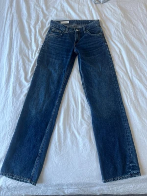 Mörkblå raka jeans - Snygga mörkblå jeans med rak passform och klassisk femficksdesign. Jeansen har normal midja och subtila slitningar för en avslappnad look. Perfekta till en enkel t-shirt eller hoodie. Materialet är denim i bomull. Oanvända. Nypris: 799kr