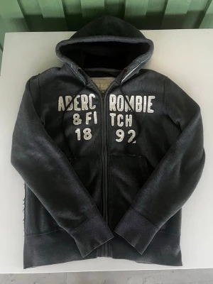Abercrombie & fitch zip hoodie grå (eftertraktad) - Riktigt snygg och eftertraktad Abercrombie & fitch zip hoodie. fint skick inga fel storlek L kan ta mått vid behov. Endast 400kr ej hugget i sten kom gärna med frågor och prisförslag har även mycket mer liknande i min profil alla storlekar kolla gärna stor rabatt vid köp av flera 😁✌️