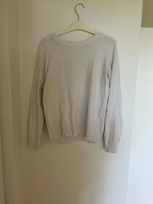 Vit stickad tröja - En enkel och stilren vit stickad tröja med rund halsringning och ribbade muddar vid ärmslut och nederkant. Perfekt basplagg till garderoben och lätt att matcha med olika outfits.
