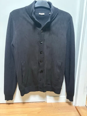 Stenströms cardigan - Snygg stenströms cardigan i merinoull med alcantara framtill. Pärlemorknappar och fickor i sidan. Använd 1-2 ggr, storlek medium, nypris är 3200 kr