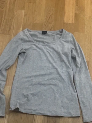 Ljusgrå tajt långärmad topp från Gina tricot - En enkel och stilren ljusgrå långärmad topp från Gina tricot. Tillverkad i mjuk bomull med rund halsringning och normal passform. Perfekt basplagg att matcha med olika stilar.