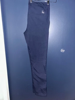 Mörkblå golfbyxor puma W29 L32 - Snygga mörkblå golfbyxor med smal passform och klassiska bakfickor. Byxorna har bälteshällor och är tillverkade i ett mjukt stretcit träningsmatrial som ger en stilren look. Perfekta för dig som vill ha en clean och soft look på golfbanan i sommar