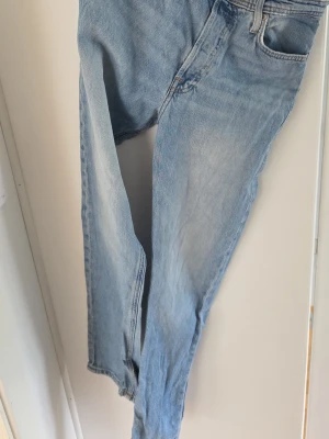 Ljusblå raka jeans från jack and jones - Säljer ett par blå jeans med rak passform och klassisk femficksdesign. Jeansen har normal midja och är tillverkade i denim. Perfekta för en avslappnad och trendig look. Size w28 L32