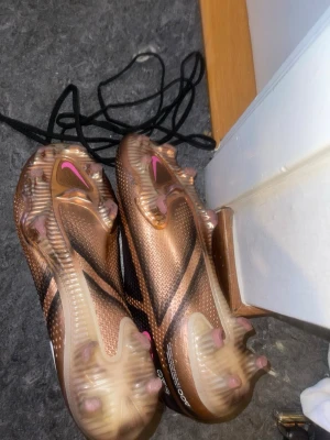 Nike Phantom Elite FG Toppmodell - Nike Phantom Elite FG Toppmodell Säljer ett par Nike Phantom Elite FG i mycket fint skick. Det är elitmodellen (toppmodellen), vilket innebär bästa kvalitet och prestanda från Nike. Skorna användes endast 3 gånger eftersom de visade sig vara för små. Därefter har de bara legat hemma och inte använts. De är därför i väldigt bra skick med minimala bruksspår, vilket också syns på bilderna.
